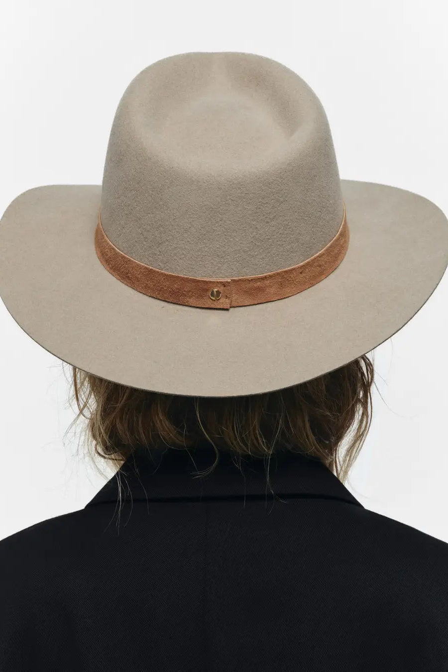 Beige wide-brimmed hat with brown band worn by a person on a white background